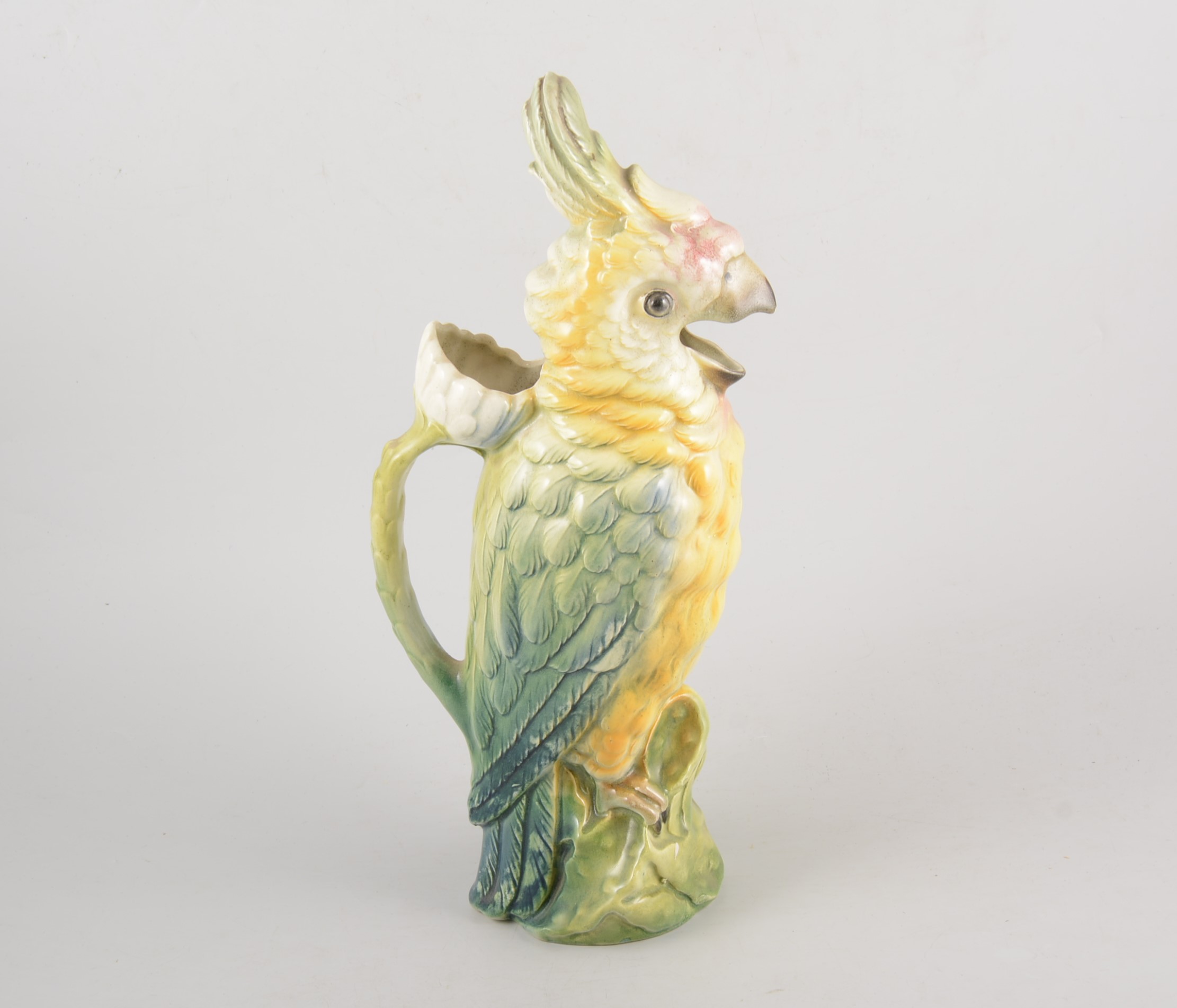 Continental ceramic jug in the form of a parrot, the handle a flower stalk, 35cm high.