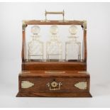 An Edwardian oak tantalus, silver plated mounts, three cut glass decanters, drawer base, 37cm.