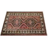 Caucasian pattern rug, two joined medallions, on a patterned red field, the border within guards,