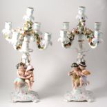 A pair of Sitzendorf candelabra, modelled with young figures holding produce of fruit,