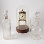 An anniversary clock under a dome, two glass decanters, one with a silver coloured rim,