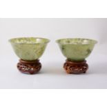 A pair of modern seaweed jade bowls, 10cm diameter, 5cm high, with small wooden stands.