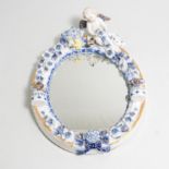 A mirror with blue and white ceramic frame, putti to top and candle holder to each side,