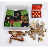 A box of military cap badges and buttons, mostly loose.