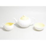 A Susie Cooper three piece teaset, white flute design with yellow interior and cover to teapot.