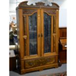 Edwardian walnut double wardrobe, carved and shaped pediment, and the doors with glazed panels,