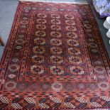 A red ground Bokhara rug, bordered and decorated with geometric gulls,