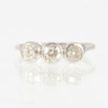 A diamond three stone ring, the old brilliant cut stones collet set in an all white metal mount,