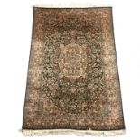 Kashmir silk rug, central floral medallion and field on a dark blue ground within guards,