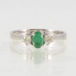 An emerald and diamond three stone ring, the oval mixed cut emerald 6mm x 4mm,