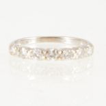 A diamond half eternity ring, seven brilliant cut diamonds claw set in an all white metal mount,