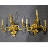 A pair of gilded rococo style wall light fittings, three lights to each, overall width 50cm.