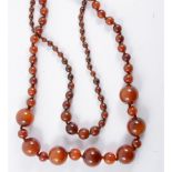 Two amber coloured bead necklaces, a 50cm row of graduated beads and 70cm row of 25mm and 8mm beads.