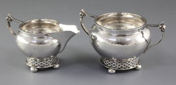 A George V planished silver Arts & Crafts sugar bowl and cream jug, by Albert Edward Jones,