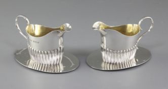 A pair of Edwardian demi fluted silver cream jugs on integral stands, hallmarked Birmingham 1904,