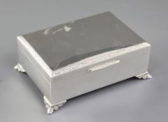 A 1960's silver rectangular cigarette box, with engraved border and thumbpiece, on cast foliate