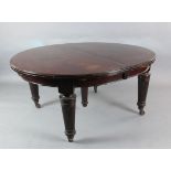 A large Victorian mahogany extending dining table with four leaves on reeded turned tapered legs 4ft