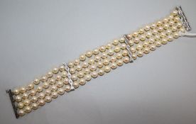 A triple strand cultured pearl bracelet with diamond set white metal clasp and spacers, 19cm.