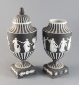 A pair of Wedgwood black jasper urn shaped vases and a cover, c.1913, applied with dancing maidens