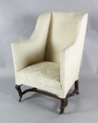 An early 19th century mahogany wing armchair with carved cabriole legs, H stretcher and brass