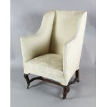 An early 19th century mahogany wing armchair with carved cabriole legs, H stretcher and brass