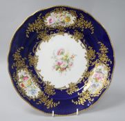 A Coalport cabinet plate, finely painted with floral reserves within gilt foliate cartouches, on a