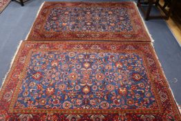 A pair of Persian red and blue ground rugs, with foliate scroll decoration and three row border, 6ft