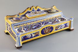 A Gien faience inkstand, c.1880, of shaped rectangular form, with arched cresting over two inkpots