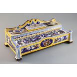 A Gien faience inkstand, c.1880, of shaped rectangular form, with arched cresting over two inkpots