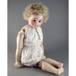 A late 19th century German bisque head doll with glass eyes, pierced ears and composition body,