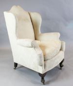 A 1920's Georgian style mahogany wing armchair with cabriole legs and brass casters H. 3ft 8in.