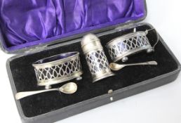 A silver three-piece condiment set, cased, with two spoons