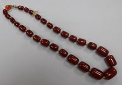 A single strand graduated simulated cherry amber barrel shaped bead necklace, gross weight 68 grams,