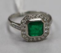 An Art Deco style platinum, emerald and diamond cluster ring, size P.