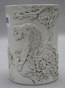 A Chinese biscuit porcelain brush pot, seal mark 'Wang Binrong', modelled in relief with a tiger