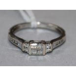 A modern 18ct white gold and Princess cut diamond set dress ring, with diamond set shoulders, size