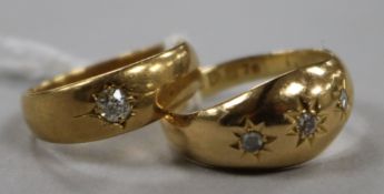 A late Victorian 18ct gold and gypsy set solitaire diamond ring and a similar George V three stone