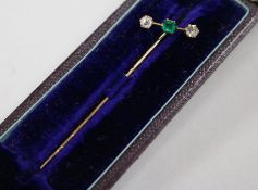 A diamond and emerald-set yellow metal stickpin, cased, 61mm.