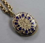A yellow metal and enamel oval locket on a yellow metal chain.