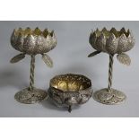 An Indian white metal footed bowl and a pair of white metal lotus shaped decorated cups.