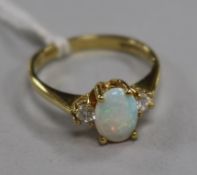 An opal and diamond three-stone ring, the opal flanked by two brilliants, 18ct gold setting, size