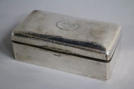 A George V hammered silver cigarette box, 19.6cm.