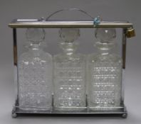 A 1930's chromed metal tantalus, fitted with three cut glass decanters, later padlock, 30cm