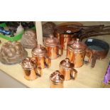 A graduated set of lidded copper measures, a group of copper saucepans and three jelly moulds