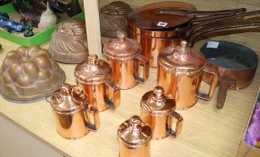 A graduated set of lidded copper measures, a group of copper saucepans and three jelly moulds