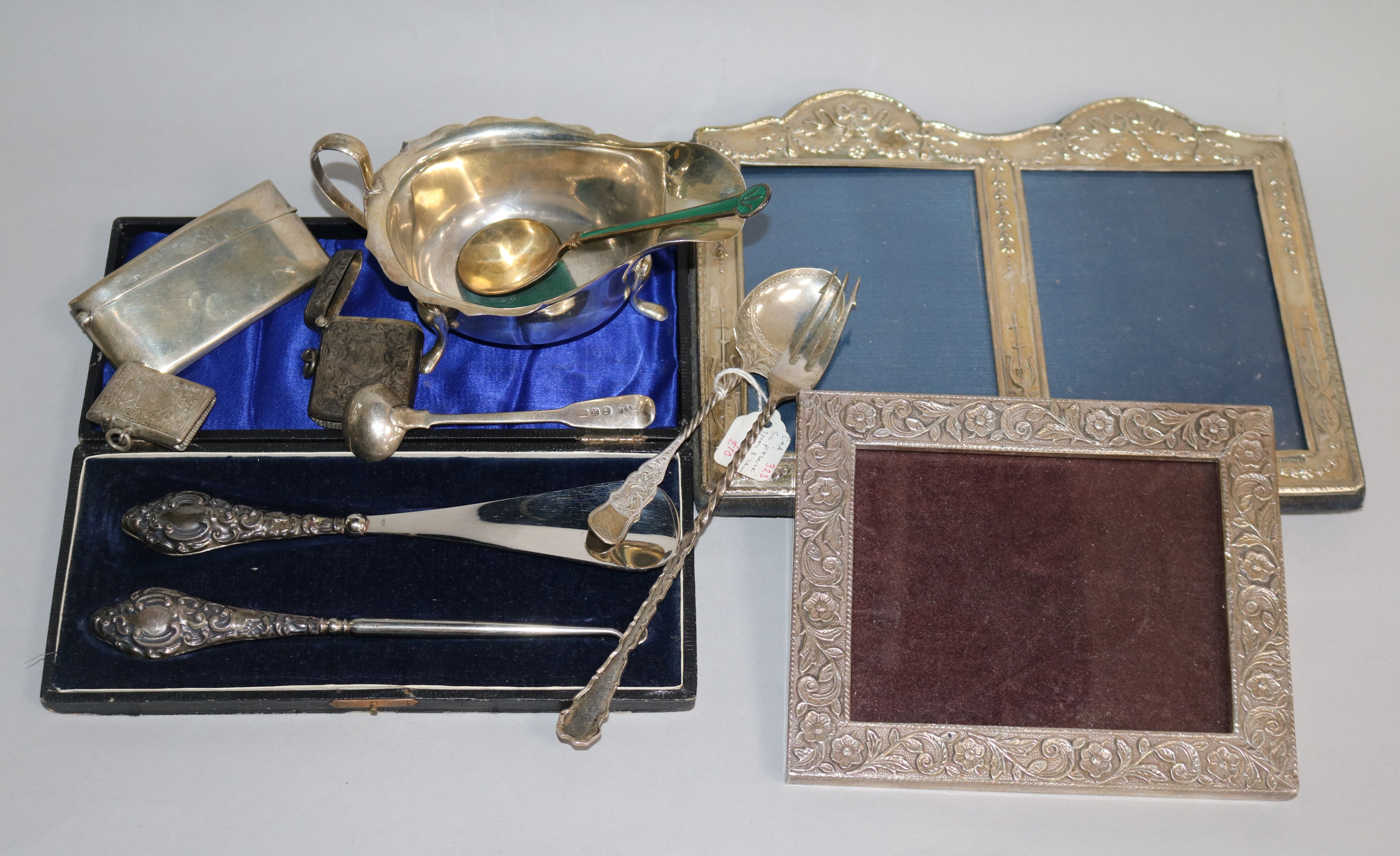 A silver mounted double photograph frame, a silver sauceboat, silver card case, silver vestas etc.