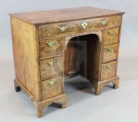 A George II featherbanded walnut kneehole desk, fitted with seven drawers around a central cupboard,