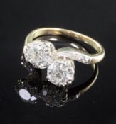 A gold and platinum, two stone diamond cross over ring, with diamond set shoulders, each large