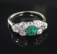 A mid 20th century white gold, emerald and diamond dress ring, the central emerald flanked by six