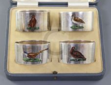 A cased set of four George V silver and enamel serviette rings, each decorated with game birds,